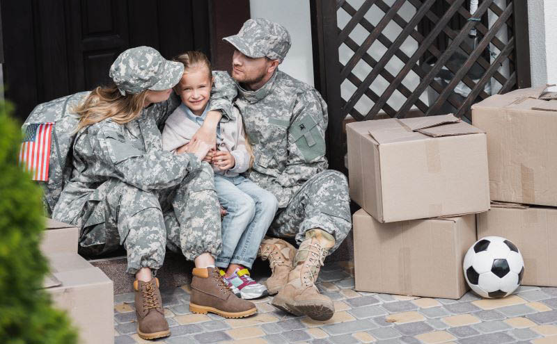 military family in front of home with boxes